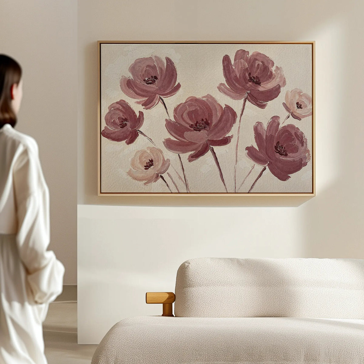 A person in a white outfit stands near a beige sofa, admiring the Autumn Rose Canvas Art—a vintage-inspired floral piece with pink long-stemmed flowers. Its soft, minimalist aesthetic adds elegance to the living room decor.