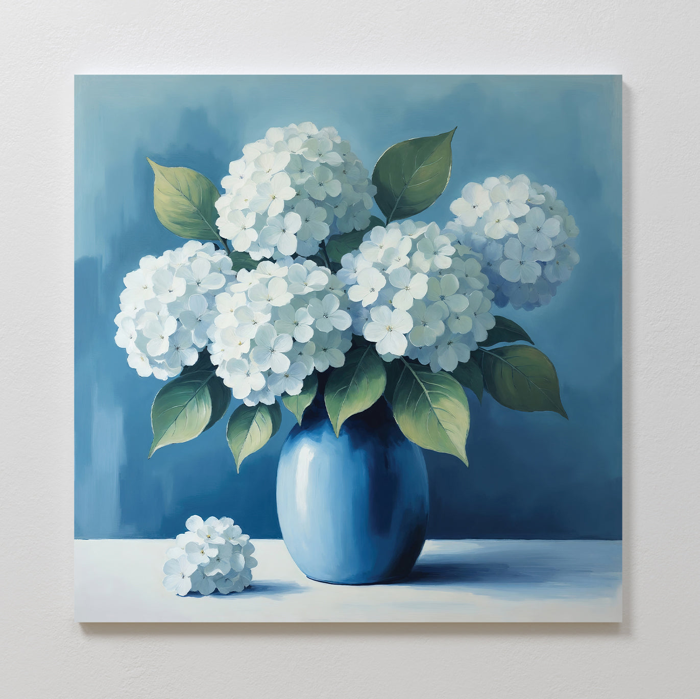Brighten your living room with Azure Cluster Canvas Art—a print featuring white hydrangeas and green leaves in a blue vase against a blue background. This elegant floral wall art adds charm to any light-colored wall decor.