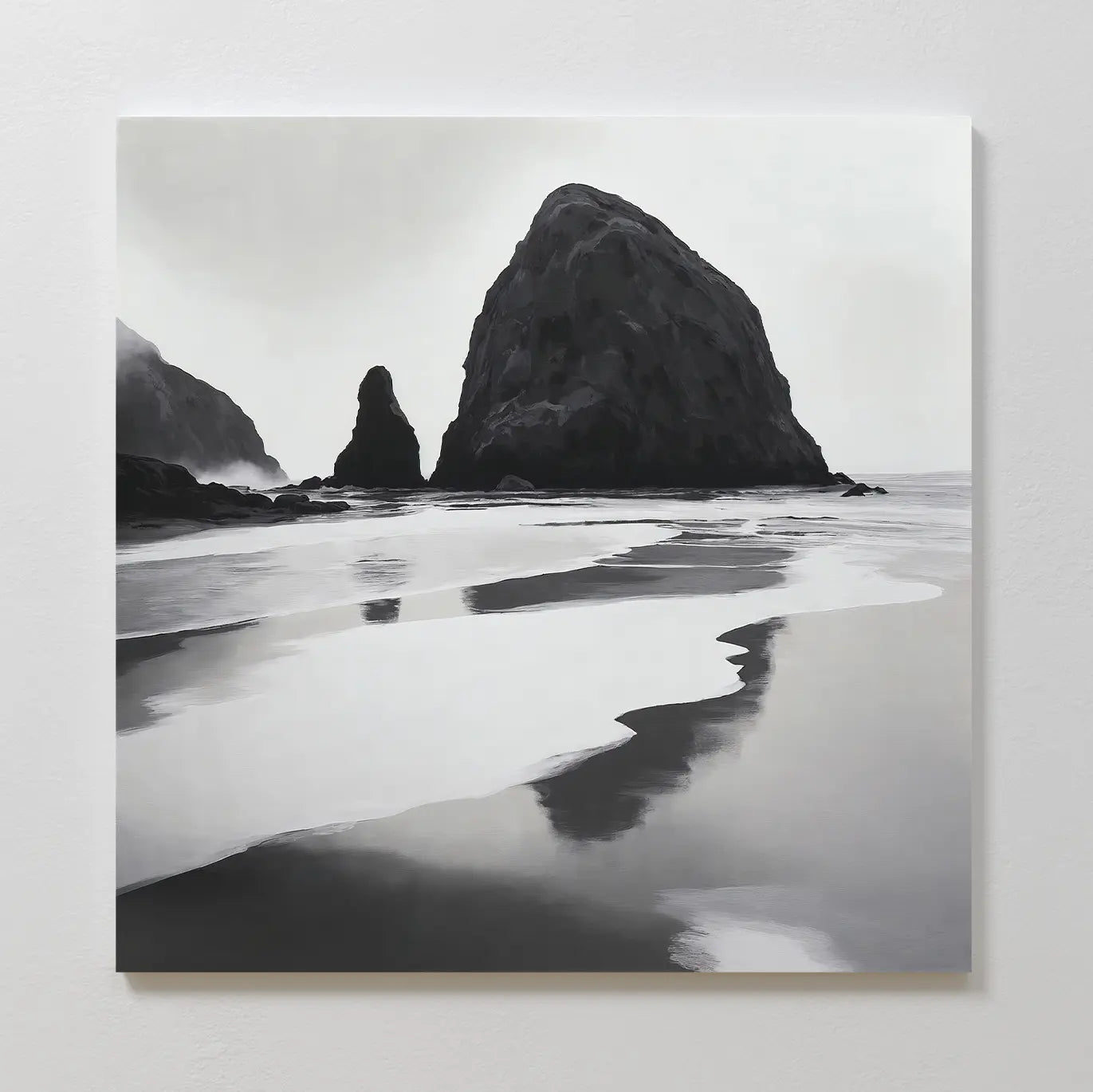 Basalt Beach Canvas Art features black and white wall art of a rocky coast with sea stacks reflected in wet sand under cloudy skies. This minimalist piece adds a calm, moody touch to modern bedrooms and looks stunning on a white wall.