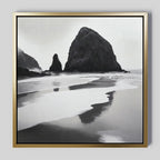 Basalt Beach Canvas Art features black-and-white framed photography of large rock formations reflected in wet sand under an overcast sky—ideal wall art for minimalist coastal décor.