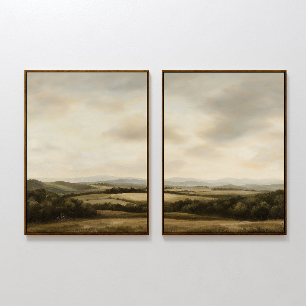The Beneath The Clouds Set of 2 features framed landscape canvases with rolling green hills, open fields, and a cloudy sky in soft neutral tones, displayed side by side on a plain white wall for a minimalist look.