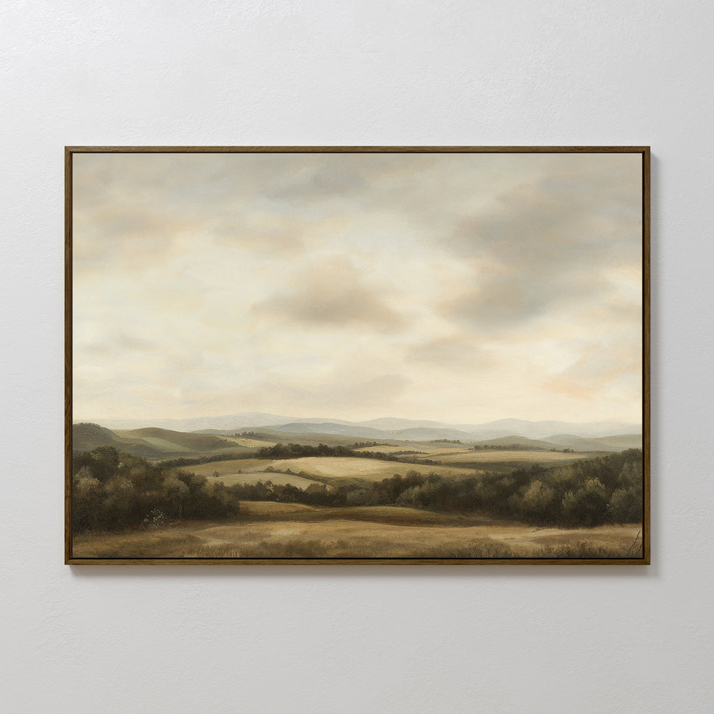Beneath The Clouds Canvas Art: A framed minimalist landscape featuring rolling hills, scattered trees, and a cloudy sky in soft muted tones, displayed on a plain white wall.