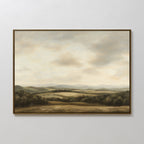 Beneath The Clouds Canvas Art: A framed minimalist landscape featuring rolling hills, scattered trees, and a cloudy sky in soft muted tones, displayed on a plain white wall.