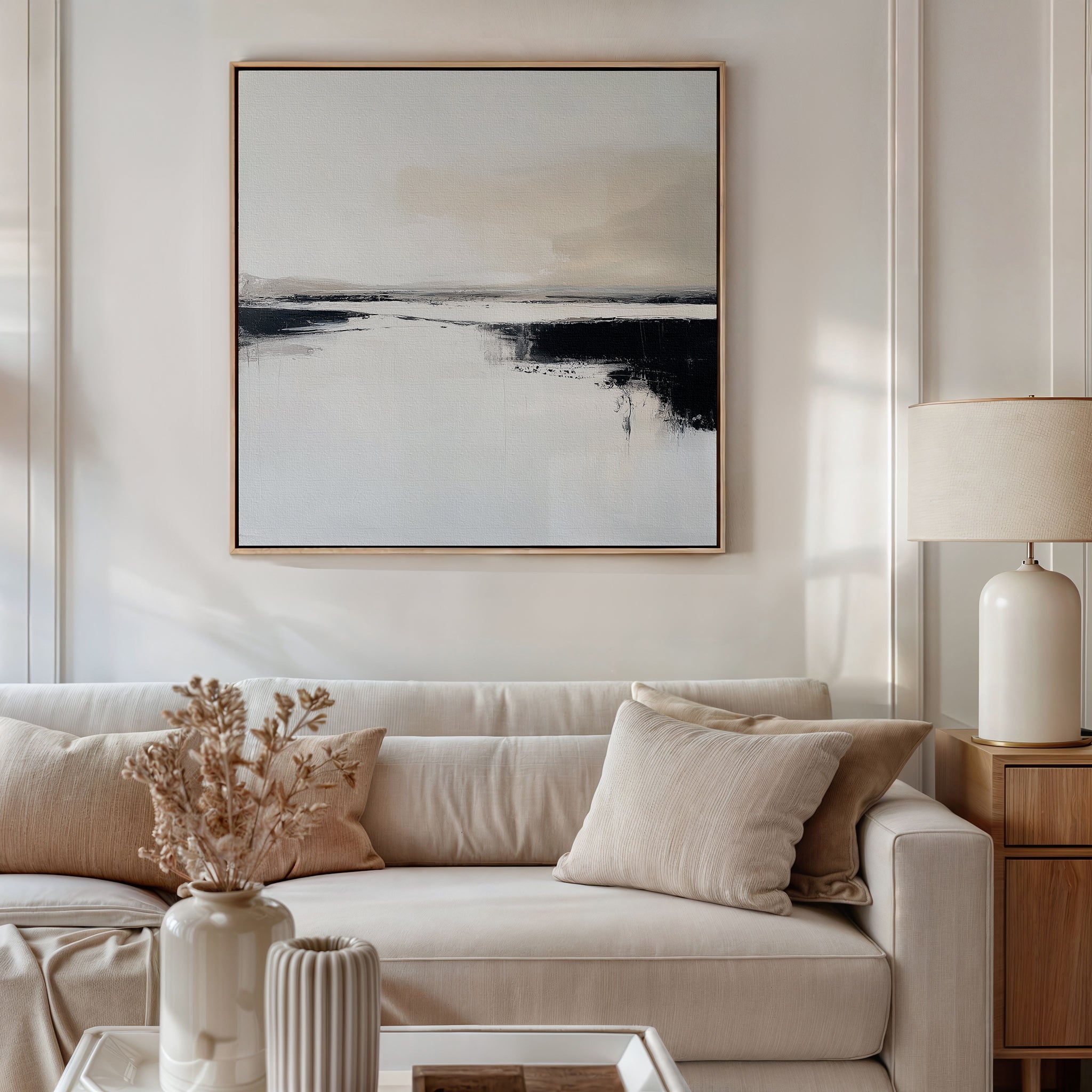 A neutral-toned living room with a beige sofa, cream pillows, a white lamp on a side table, dried flowers in a vase, and the Binary Calm Abstract Canvas Art above the sofa adds modern elegance.
