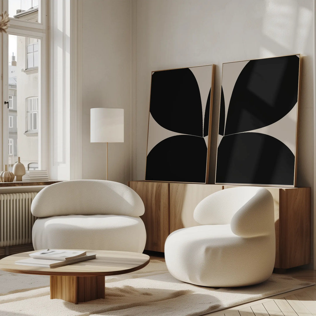 Bright, modern living room with Minimal Petal Set of 2 rounded white chairs, a wooden coffee table, a floor lamp, and minimalist black abstract wall art above a wooden sideboard beneath large windows.