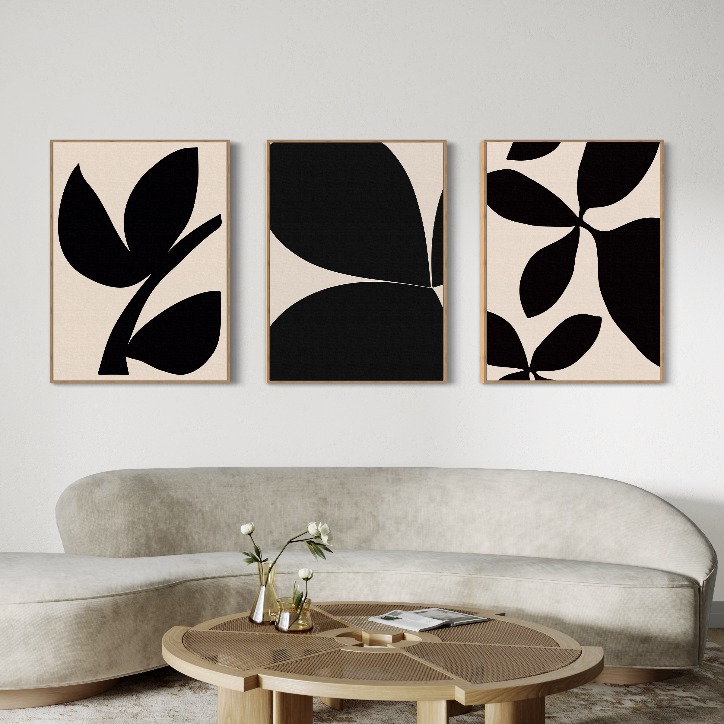 A modern living room with a curved beige sofa, a round wooden coffee table, and the Black Botanical Set of 3—abstract black-and-beige botanical wall art prints from Nordic Park—displayed above the sofa.
