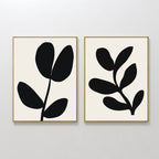 The Black Leaf Set of 2 features framed minimalist prints with abstract black leaf shapes on a white background, each showcasing a simple botanical design—perfect for striking botanical wall art.