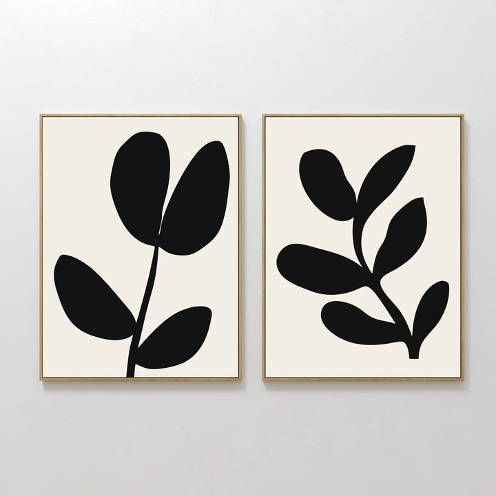 The Black Leaf Set of 2 features framed minimalist prints with abstract black leaf shapes on a white background, each showcasing a simple botanical design—perfect for striking botanical wall art.
