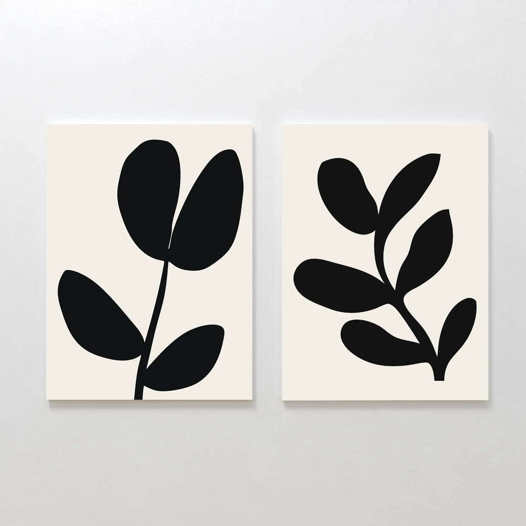 The Black Leaf Set of 2 features minimalist prints with bold black abstract plant silhouettes, each showing a stylized stem with rounded leaves—perfect botanical wall art for modern decor.