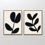 The Black Leaf Set of 2 features framed minimalist prints with black leaf shapes on a white background, creating striking botanical wall art that adds modern elegance to any space when hung side by side.