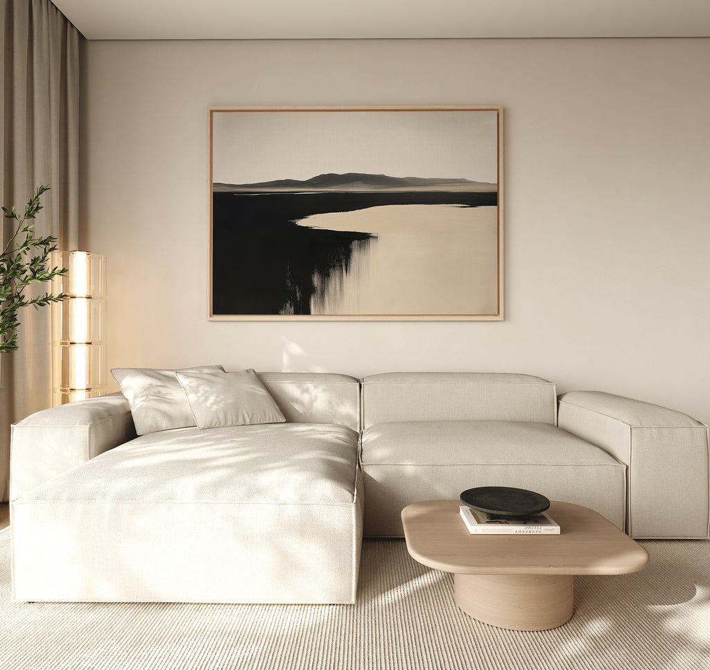 A modern living room with a beige sectional sofa, light wood coffee table, and Black Shore Canvas Art – Horizontal hanging above. Sheer curtains and a tall plant to the left complete the decor.