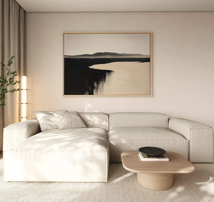 A modern living room with a beige sectional sofa, light wood coffee table, and Black Shore Canvas Art – Horizontal hanging above. Sheer curtains and a tall plant to the left complete the decor.