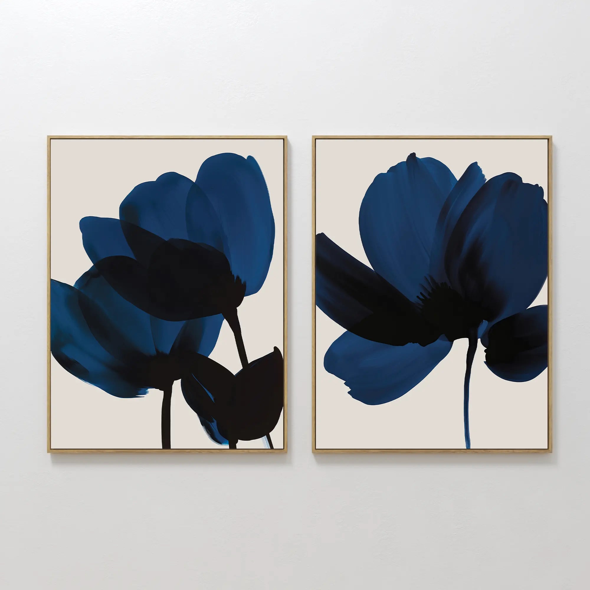 The Bloom Set of 2 features framed minimalist art of dark blue abstract flowers with black stems on light beige backgrounds, displayed side by side. This contemporary Nordic Park-inspired wall art adds a modern touch to any room.