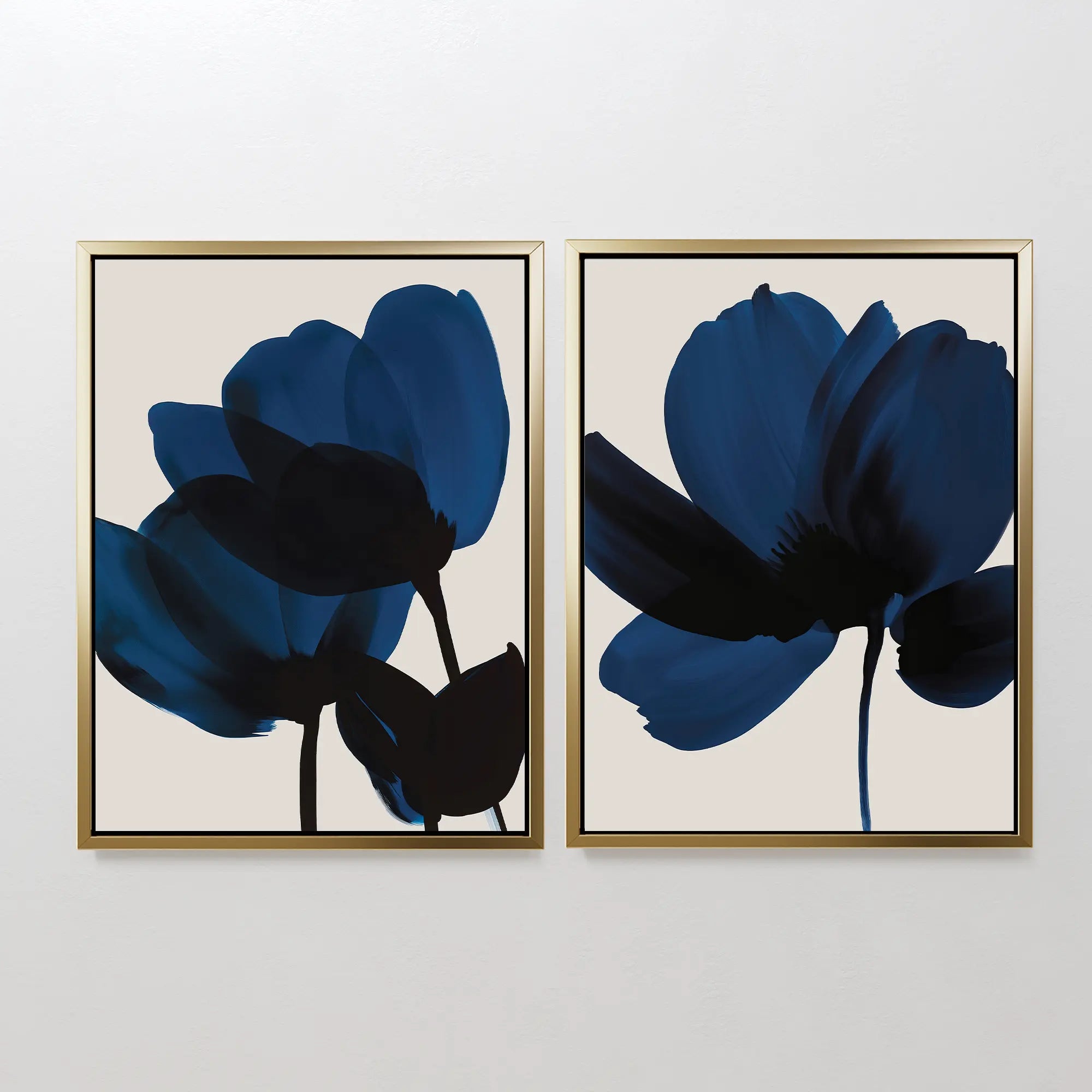 The Bloom Set of 2 features framed art prints with abstract dark blue and black floral silhouettes on a light beige background, adding modern elegance to any space when displayed side by side.