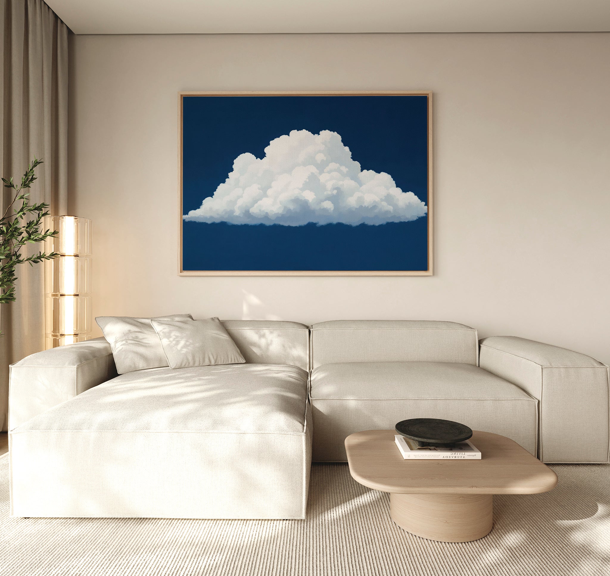 A modern living room with a beige sectional sofa, light wood coffee table, plant, and the Blue Horizon Cloud Canvas Art—a minimalist piece depicting a fluffy white cloud on a deep blue background—hanging above.
