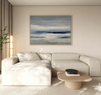 A modern living room with a light beige sectional sofa, low wooden coffee table, black bowl, tall plant, and minimalist wall art—a Blue Mist Horizon Canvas Art—serving as striking decor above the couch.