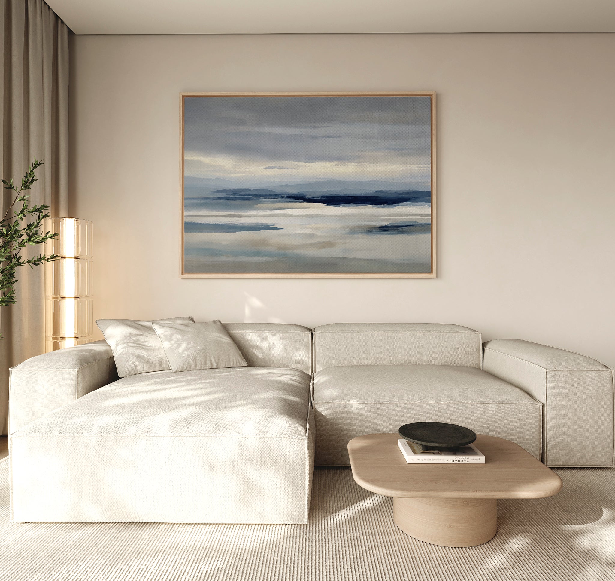 A modern living room with a light beige sectional sofa, low wooden coffee table, black bowl, tall plant, and minimalist wall art—a Blue Mist Horizon Canvas Art—serving as striking decor above the couch.