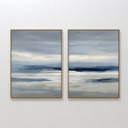 The Blue Mist Horizon Set of 2 features large abstract landscape prints in soft blue, grey, and beige. These framed canvases evoke a serene, cloudy sky, adding calming, minimalist decor to your living room when hung side by side.
