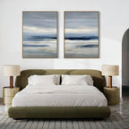Minimalist bedroom with an olive green bed and beige nightstands. Above the bed, the Blue Mist Horizon Set of 2 features large canvas prints of abstract landscapes in blue and gray, adding striking minimalist wall art.