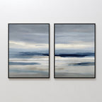 The Blue Mist Horizon Set of 2 features abstract landscape prints in soft blue, gray, and beige. These large canvases create a serene seascape, perfect as minimalist wall art for your living room, displayed side by side on a white wall.