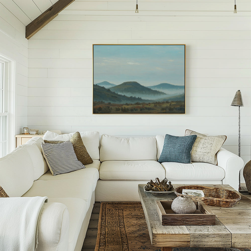 A bright, cozy living room with white shiplap walls, a spacious white sectional sofa, a rustic wooden coffee table, and tranquil Blue Ridge View Canvas Art featuring misty blue mountains displayed on the wall.