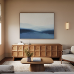 A modern living room with a wooden sideboard, the Blue Valley Mist Canvas Art on the wall, a small table with vase and book, a beige sofa, and soft neutral tones—perfect for minimalist decor.