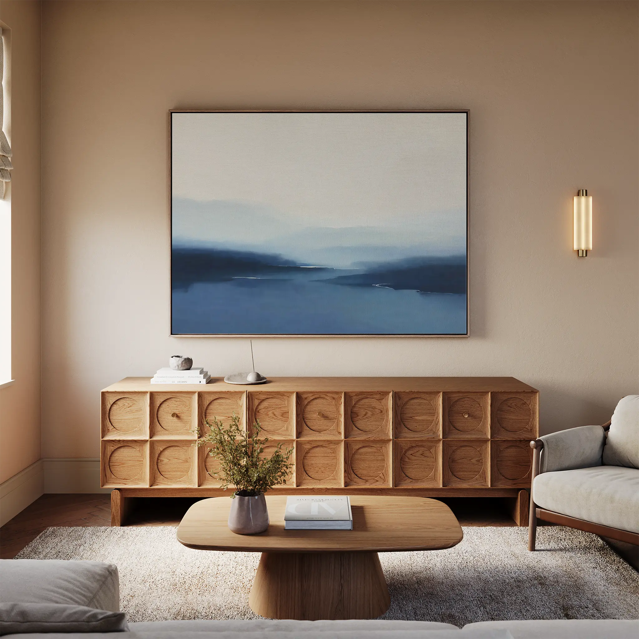 A modern living room with a wooden sideboard, the Blue Valley Mist Canvas Art on the wall, a small table with vase and book, a beige sofa, and soft neutral tones—perfect for minimalist decor.