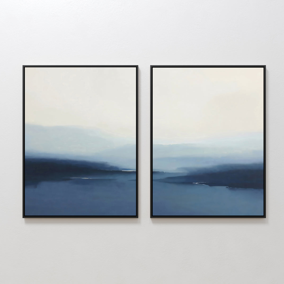 The "Blue Valley Mist Set of 2" features abstract wall art prints in soft blue and white tones, evoking misty seascapes. Displayed side by side in black frames, they bring minimalist style to any white wall.