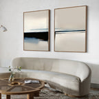 A modern living room with a curved beige sofa, a round wooden coffee table topped with a single flower in a vase, and the Blurred Reflections Set of 2 large minimalist wall art prints in neutral tones hanging above the sofa.