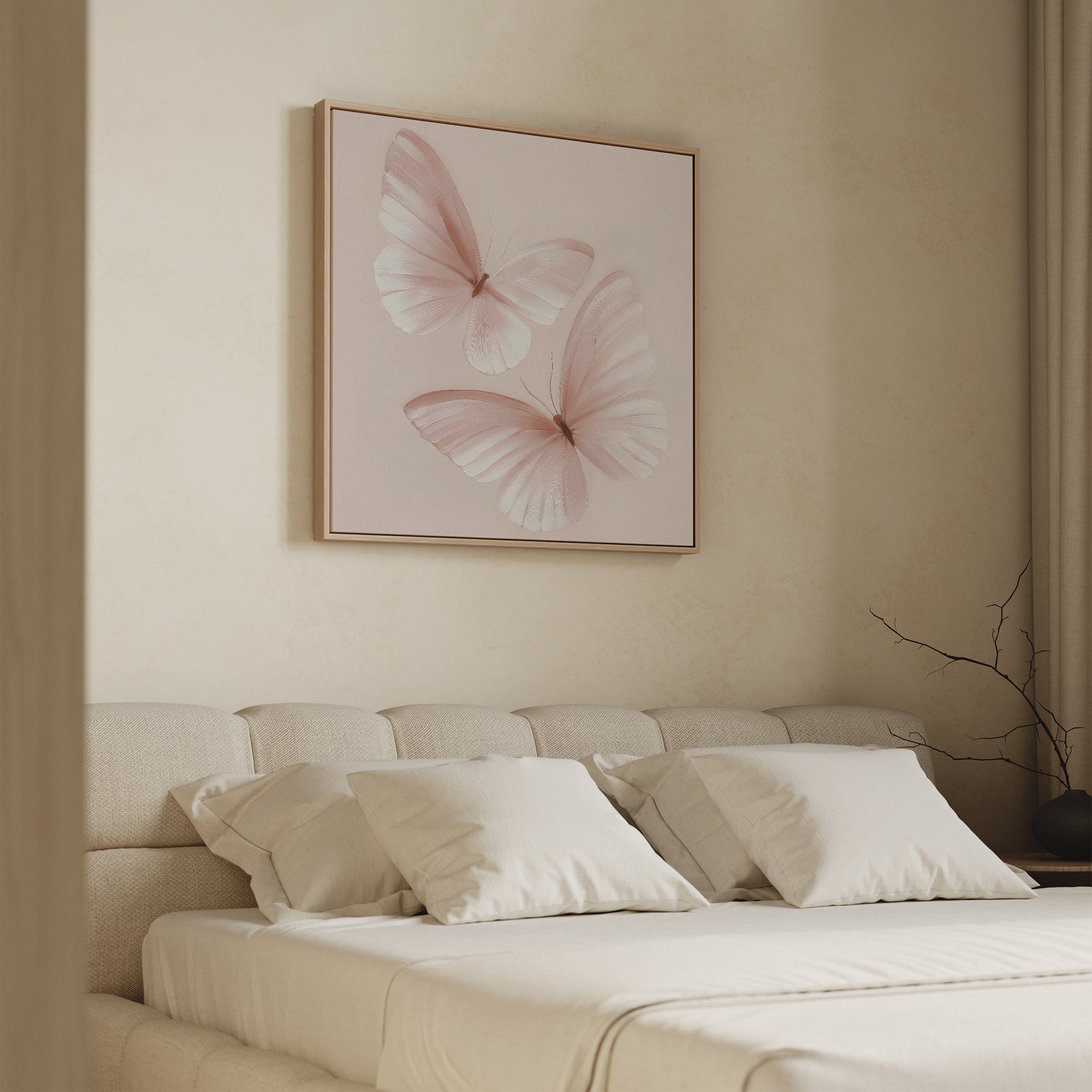 A cozy beige bedroom features an upholstered bed with cream pillows and bedding, and the Blush Wings Canvas Art with two pink butterflies above the headboard. A bare branch in a vase on the nightstand adds subtle blush pink wall decor.