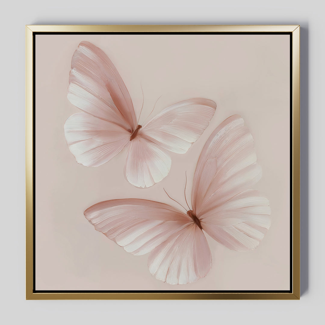 Blush Wings Canvas Art showcases two delicate pale pink butterflies with translucent wings on a soft beige background. A gold frame with a slim black inner border adds elegance to this stylish blush-toned wall decor.