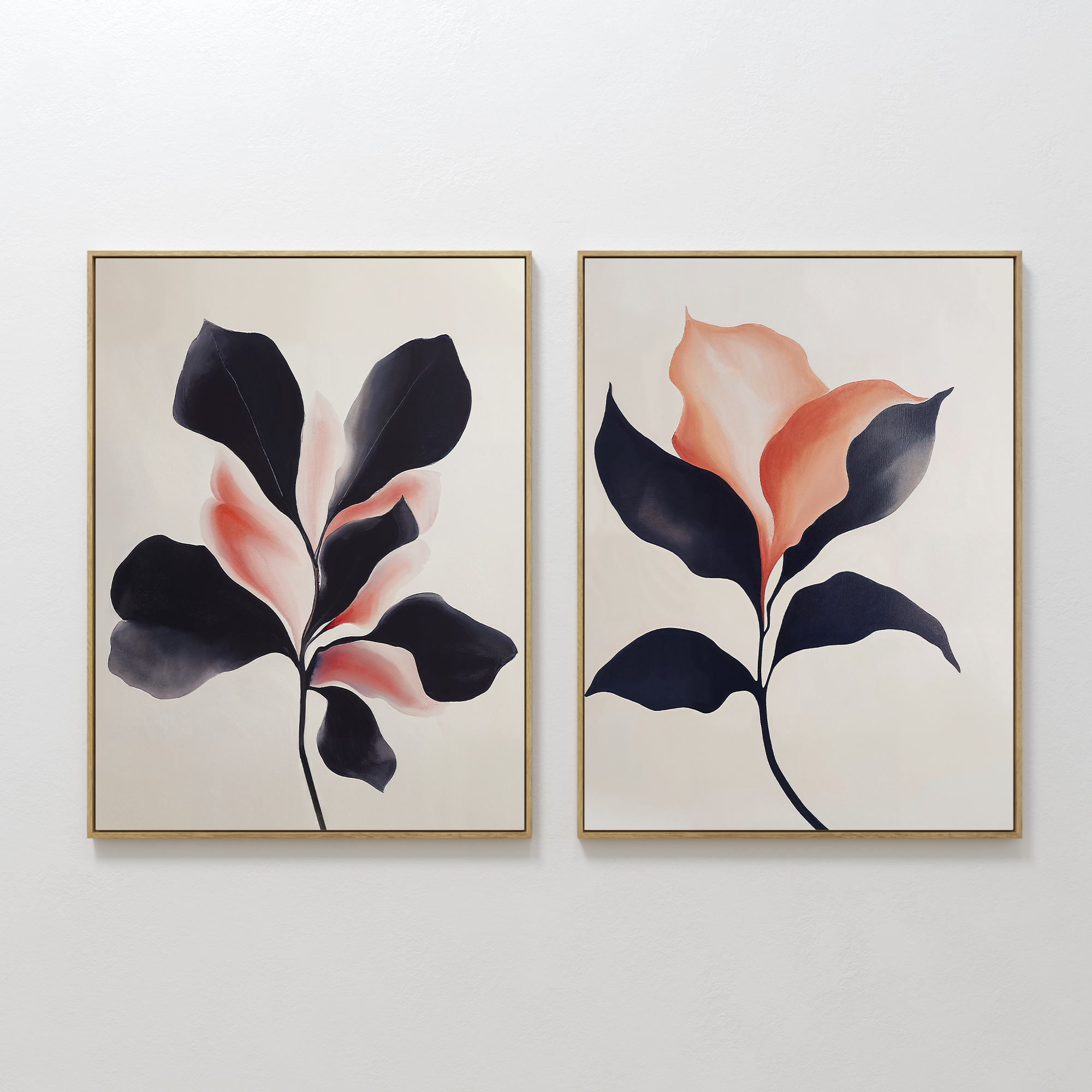 The Blush & Shadow Set of 2 features framed abstract botanical prints with stylized leaves in dark navy and soft coral, displayed side by side on a white wall. The light background enhances the organic shapes and modern color gradients.
