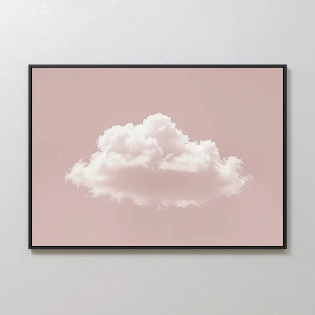 The Blushing Sky Canvas Art features a fluffy white cloud on a soft pink background, displayed on a light gray wall—an ideal minimalist decor accent and charming wall art print.
