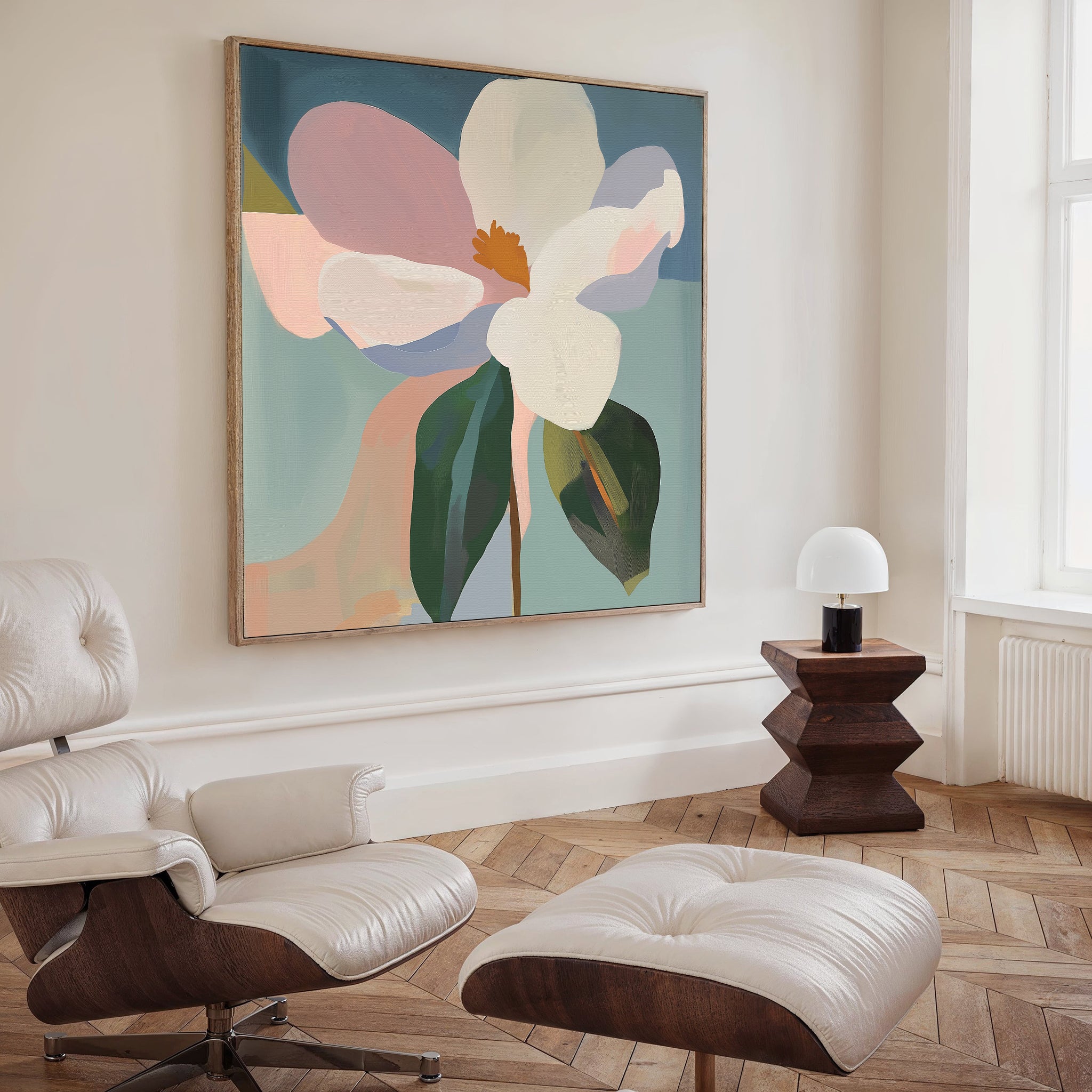 A modern living room features a white leather lounge chair and ottoman, a geometric dark wood side table with a small white lamp, and the Bold Bloom Canvas Art adding contemporary elegance above the table.