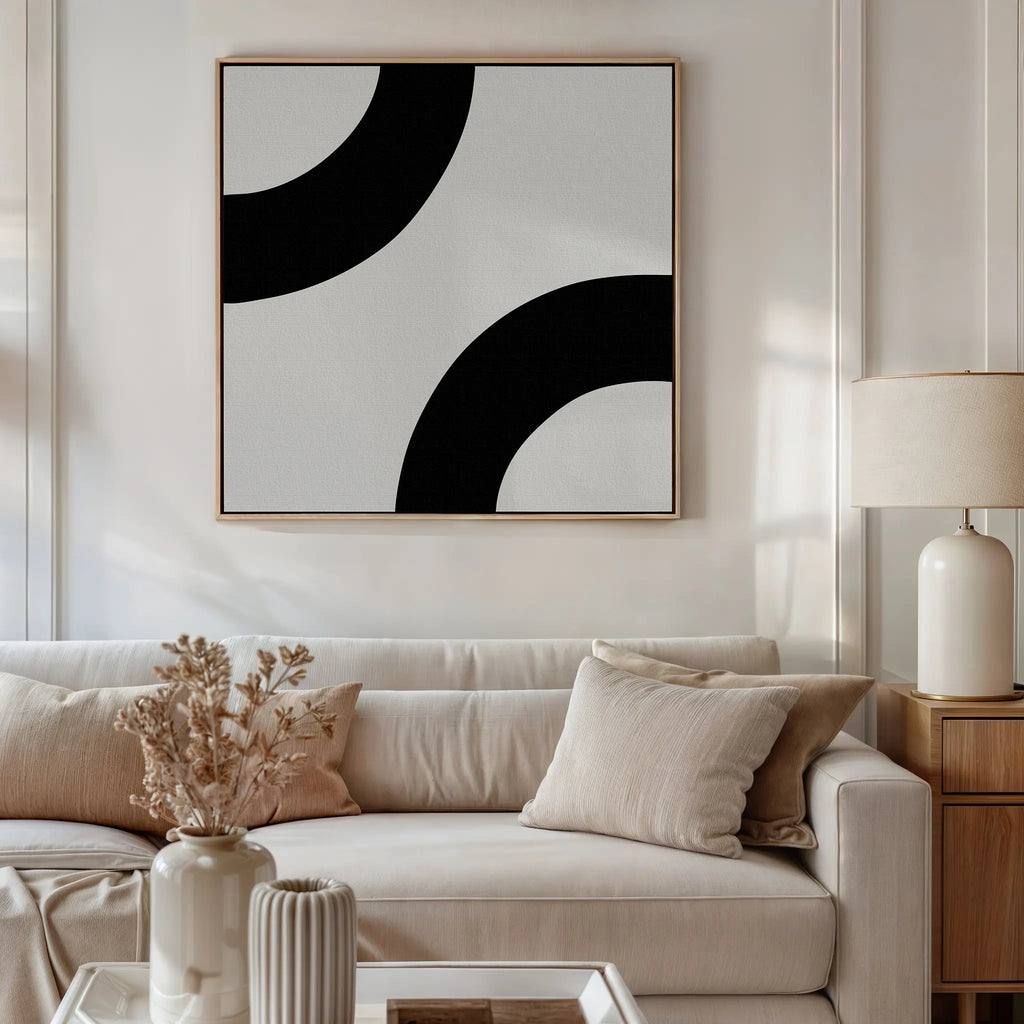 A modern living room with a beige sofa, neutral cushions, a wooden side table with a white lamp, dried flowers in a vase, and Bold Orbit Canvas Art as minimalist wall décor.