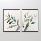 The Botanical Breeze Set of 2 features framed watercolor prints of green leafy branches on a white background, adding calming, minimalistic style and fresh green leaves decor to any room. Perfect as wall art for a tranquil atmosphere.