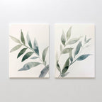 The Botanical Breeze Set of 2 features minimalist wall art prints with watercolor-style green leaves on white backgrounds, each showing a single diagonal branch—perfect for adding a fresh, modern touch when displayed side by side.