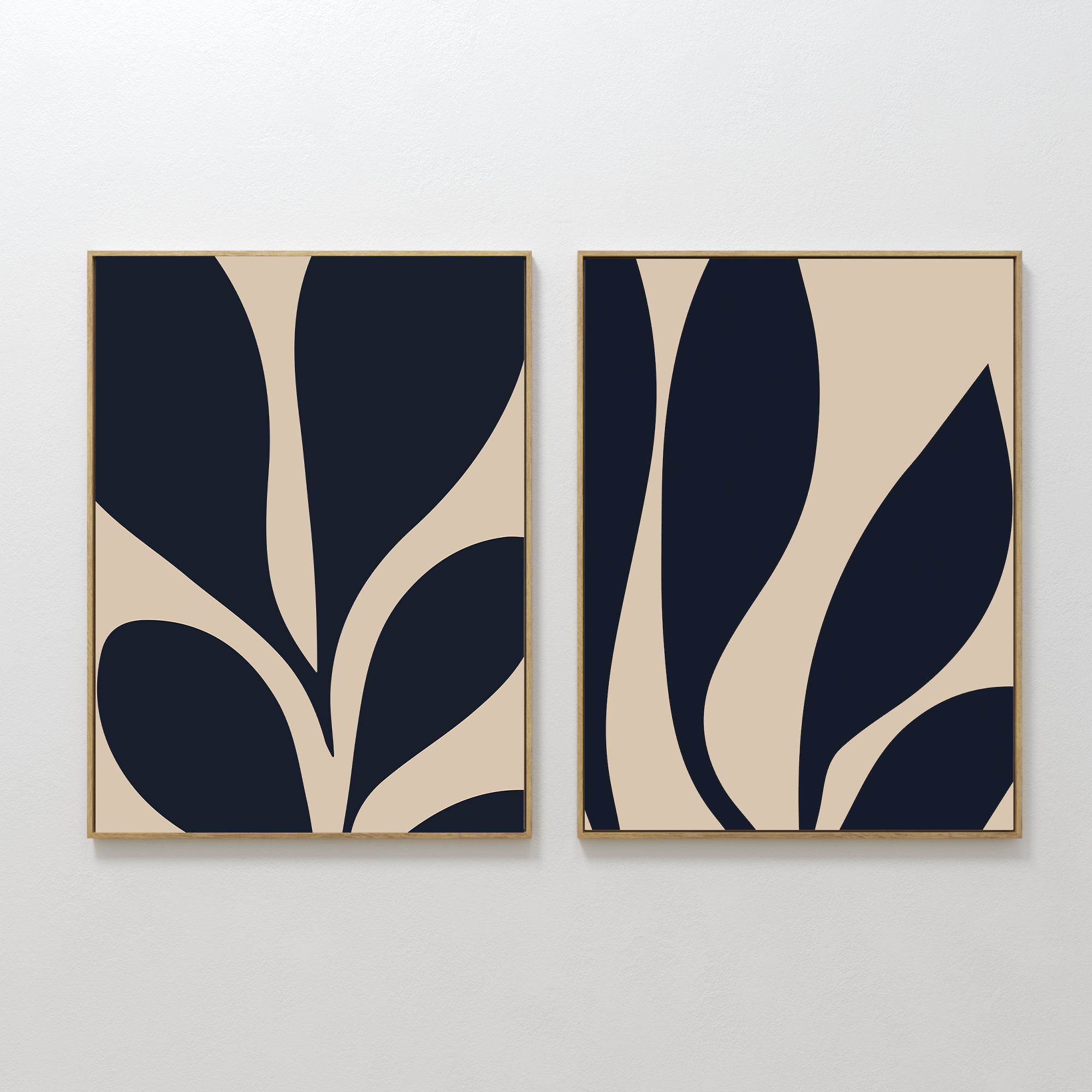 The Botanical Ink Set of 2 features framed abstract prints with bold, organic navy and beige shapes resembling stylized leaves—modern wall art perfect for your living room decor.