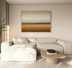 A modern living room with a light beige sectional sofa, low wooden coffee table, black bowl, tall lamp, potted plant, and Caramel Plains Canvas Art – Horizontal on the wall in earth tones.