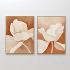 The Clay Blossom Set of 2 features framed abstract floral prints with beige and white flowers on a terracotta background. Displayed side by side, these artworks showcase soft, flowing shapes and minimal detail for a modern touch.