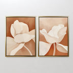 The Clay Blossom Set of 2 features framed abstract floral wall art prints with large cream and beige flowers on a warm brown background, displayed side by side on a plain white wall.