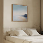 Minimalist bedroom with a beige bed, white pillows, and the Cliffside Light Canvas Art featuring a coastal landscape above the headboard. Soft natural light streams in through a window with sheer curtains.