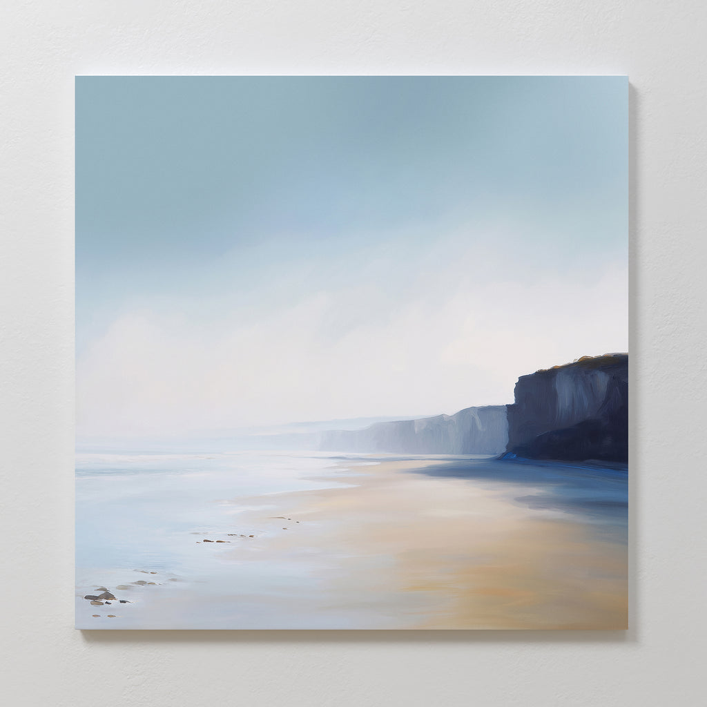 The Cliffside Light Canvas Art features a serene beach with calm water, sandy shore, and distant cliffs under a soft blue sky, adding minimalist elegance to any white wall.