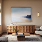 A modern living room with a light wood coffee table, textured-door sideboard, neutral rug, cream sofa, and the Cliffside Light Canvas Art – Horizontal displayed above the sideboard.