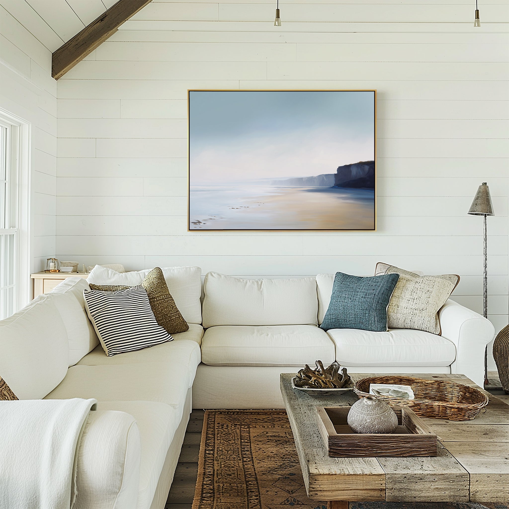 A bright, cozy living room with white shiplap walls, a large white sectional sofa, assorted throw pillows, a rustic wooden coffee table, and the Cliffside Light Canvas Art – Horizontal hanging above the couch.