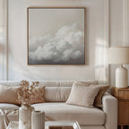 A modern living room with a beige sofa, neutral pillows, a side table with a ceramic lamp, and the Cloud Reverie Canvas Art on the wall. Dried flowers in a vase on the coffee table complete the serene atmosphere.
