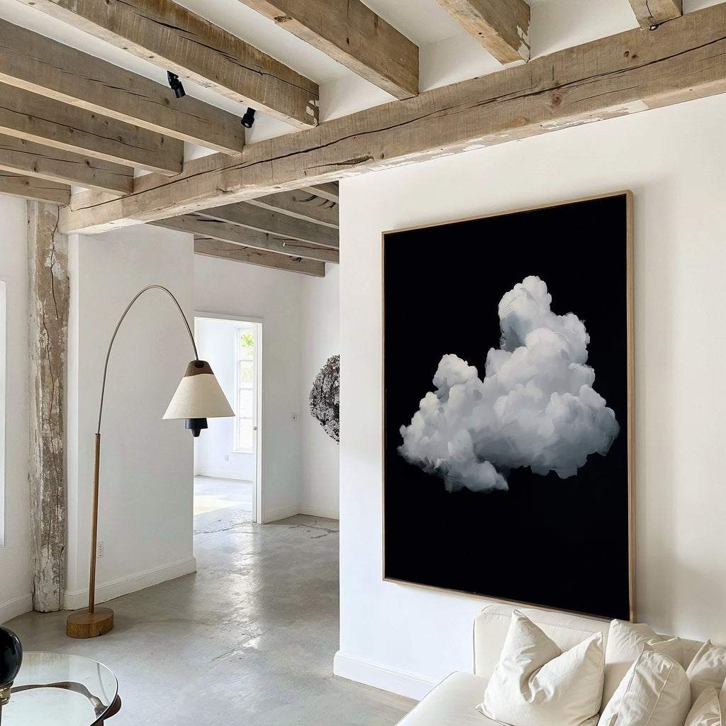 A modern living room with exposed wooden beams, white walls, a curved floor lamp, and the Cloud In Darkness Abstract Canvas Art featuring a fluffy white cloud on black displayed above a white sofa.