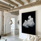 A modern living room with exposed wooden beams, white walls, a curved floor lamp, and the Cloud In Darkness Abstract Canvas Art featuring a fluffy white cloud on black displayed above a white sofa.