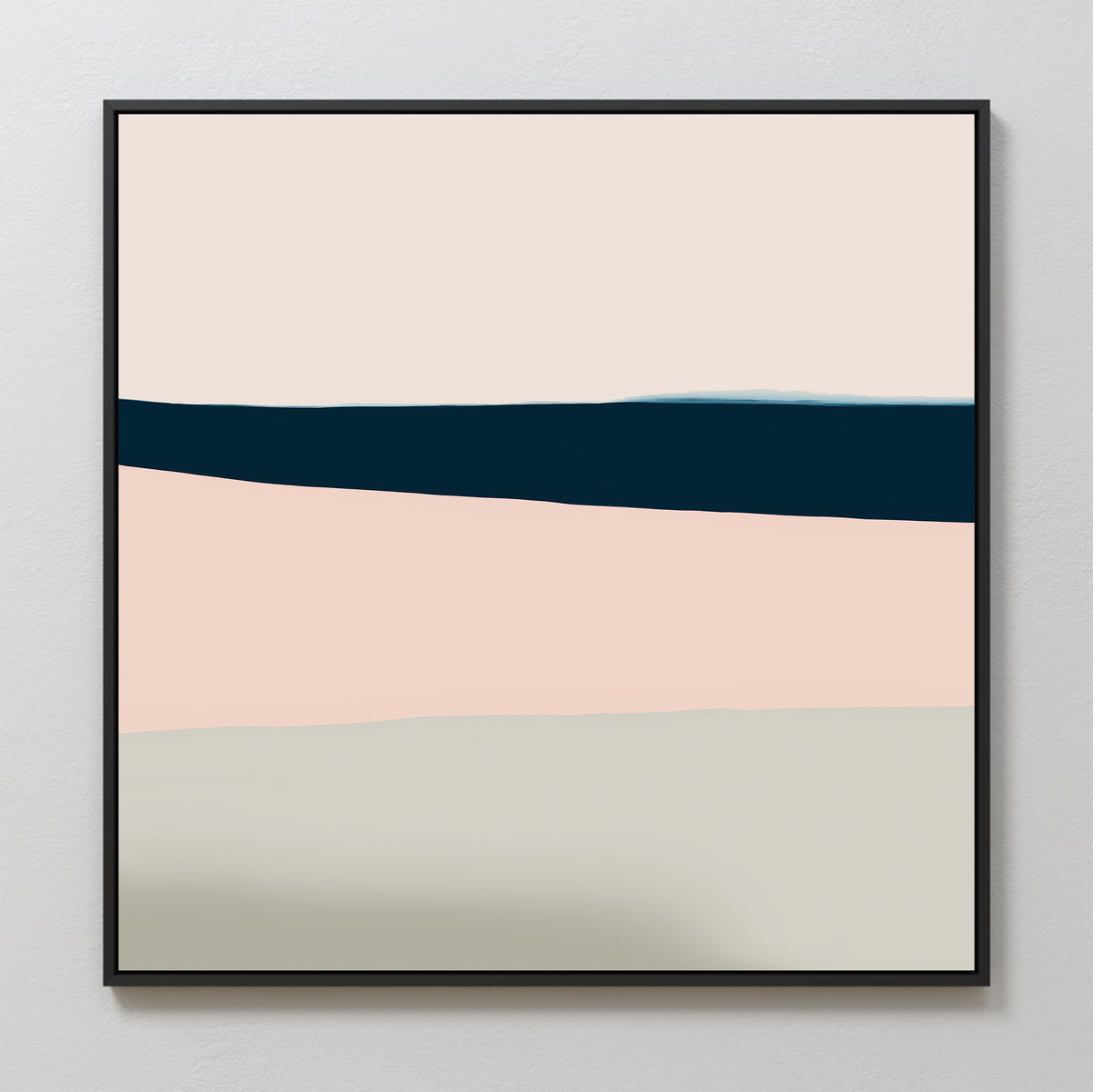 The Coastal Blend Abstract Canvas Art features horizontal bands in cream, navy blue, blush pink, and light gray with a black frame, bringing modern sophistication to any living room decor against a plain white wall.