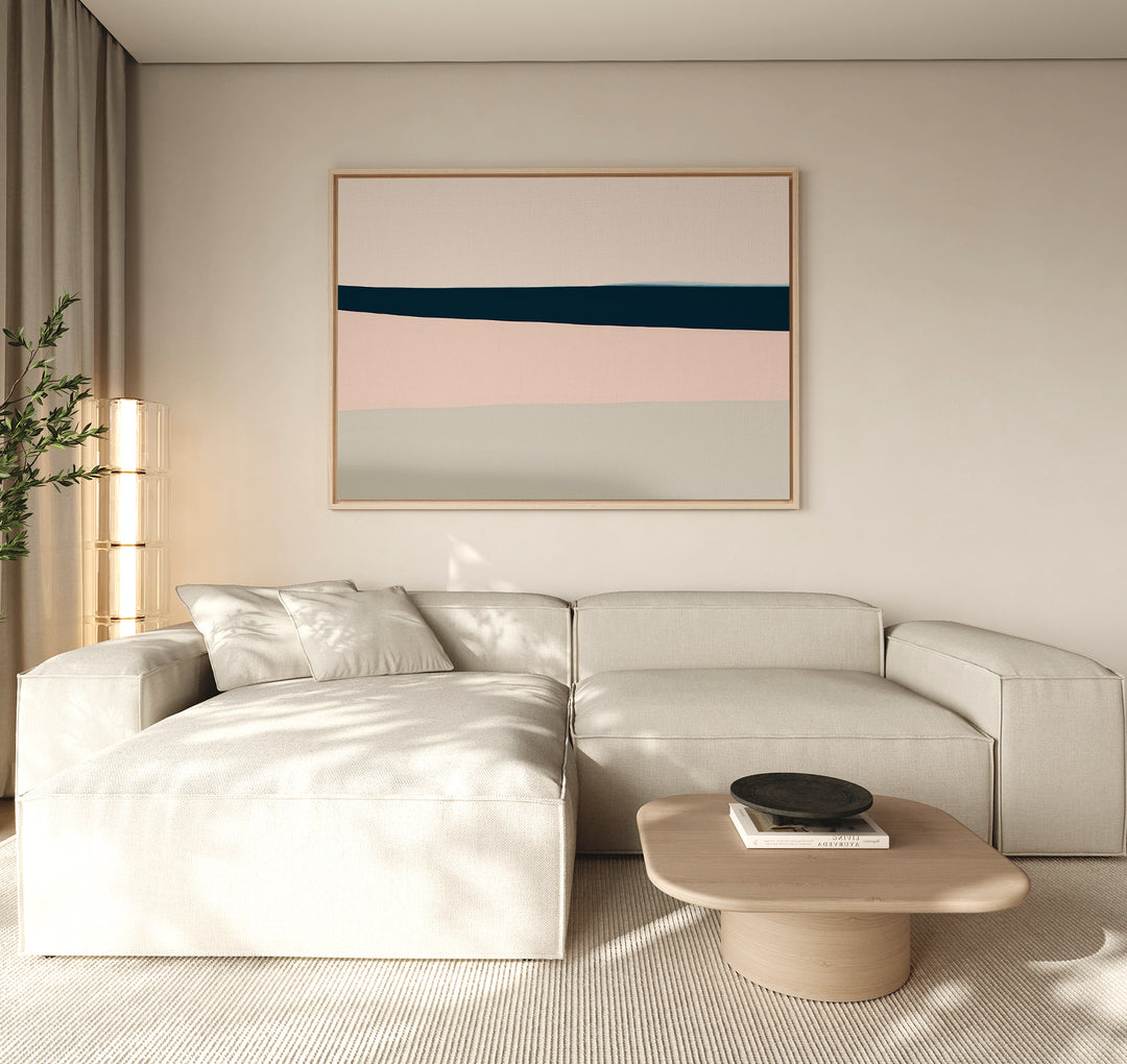 A modern living room features a cream sectional, light wood coffee table with a black bowl, beige curtains, tall plant, and minimalist decor highlighted by the Coastal Blend Canvas Art – Horizontal above the sofa.